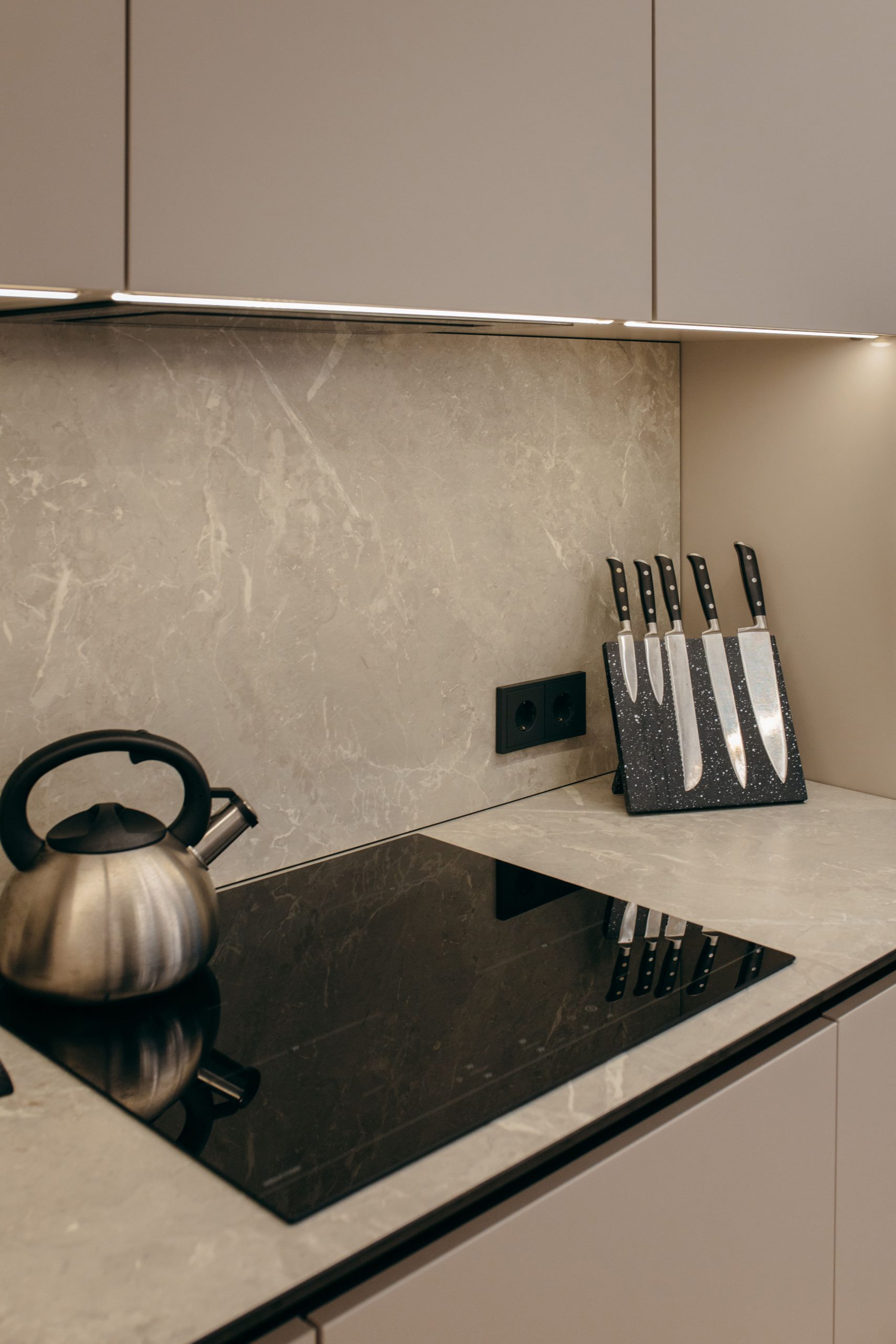 Modern kitchen stove in apartment with knives on the side and a kettle on the hob